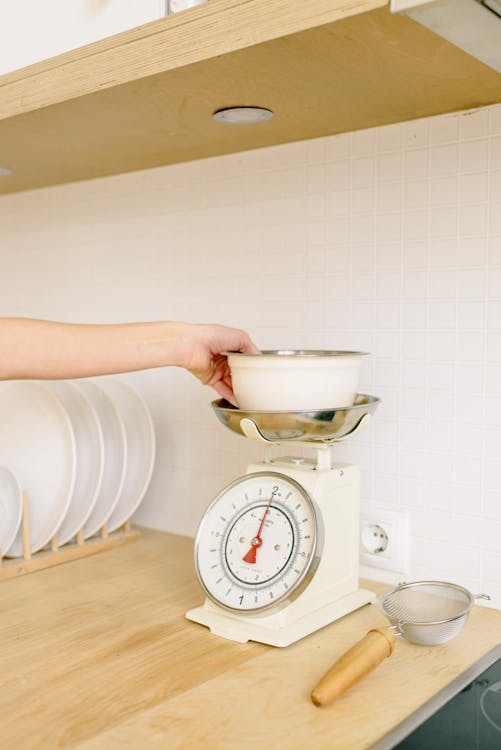 A Hand Weighing the Bowl on a Scale