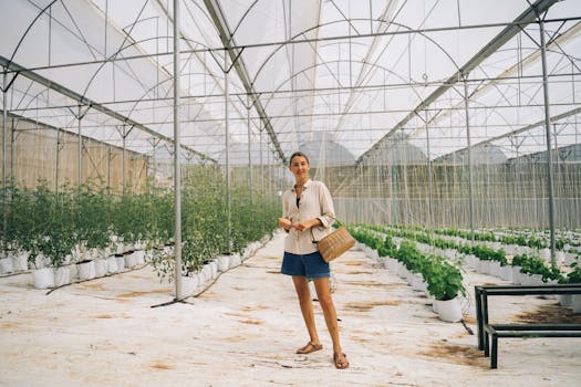 Smiling woman with a woven basket in a greenhouse, showcasing horticultural work.