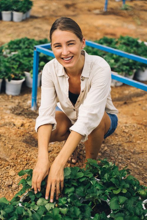 Free A cheerful woman tending to plants, showcasing joy in gardening and outdoor care. Stock Photo