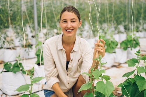 A Woman Smiling While Sitting Near Green Plants