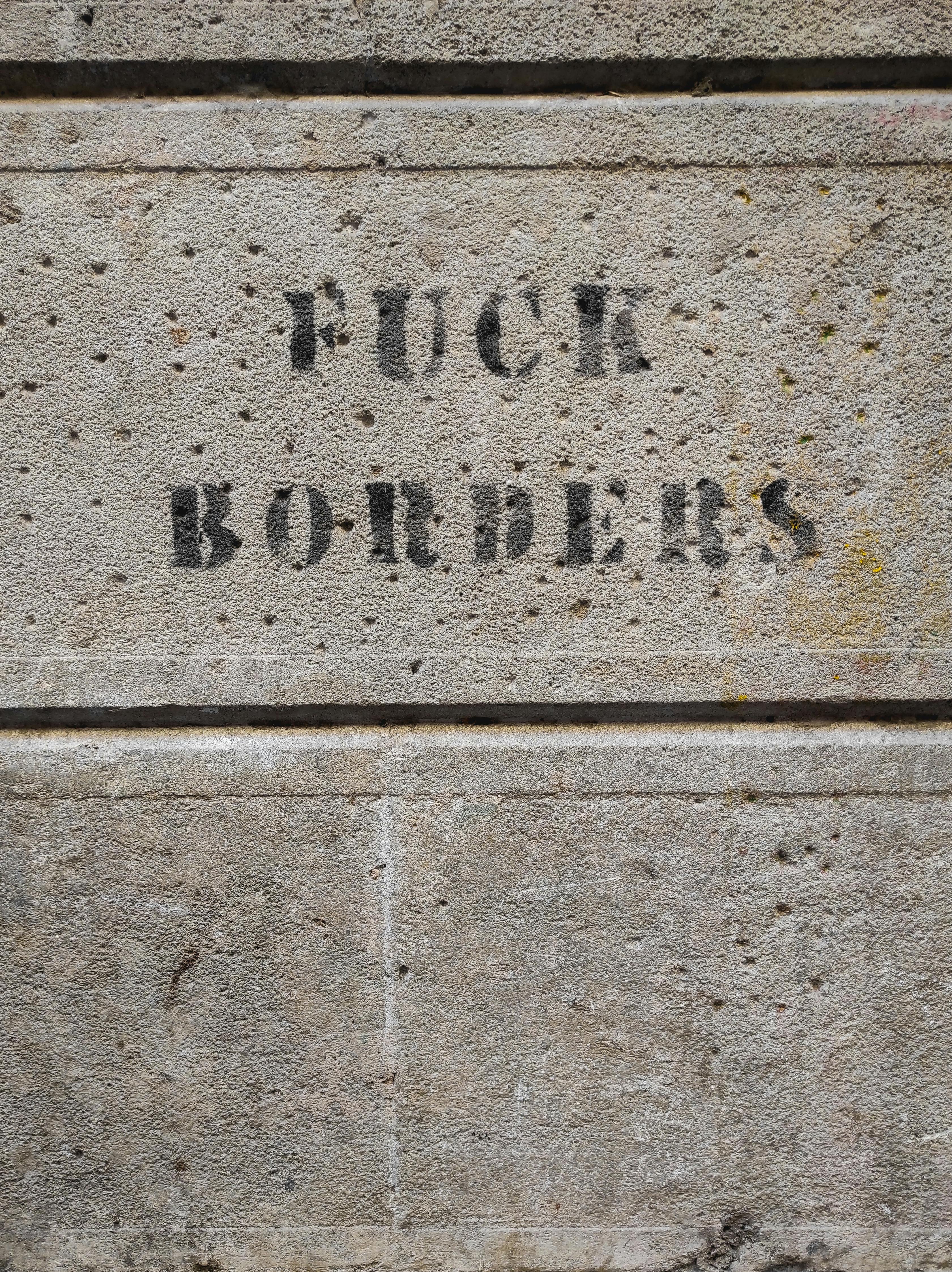 Graffiti message expressing anti-border sentiment on a concrete wall in Barcelona.