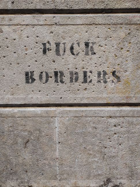 Graffiti message expressing anti-border sentiment on a concrete wall in Barcelona.