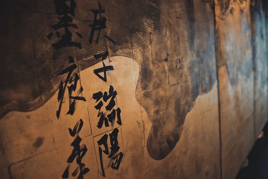 Artistic close-up of Japanese calligraphy on a textured wall, highlighting traditional elements.