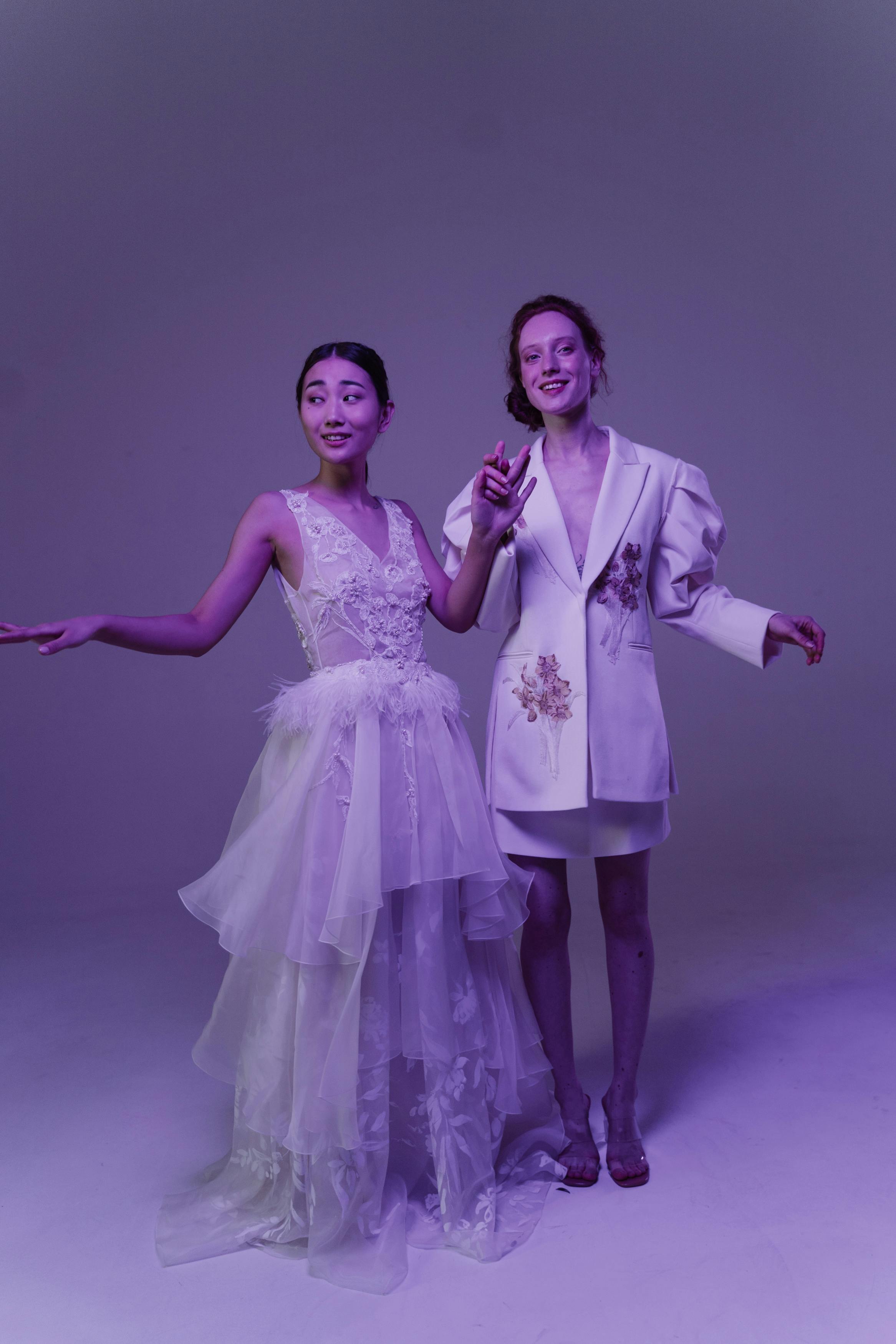 women in white dresses posing while holding hands