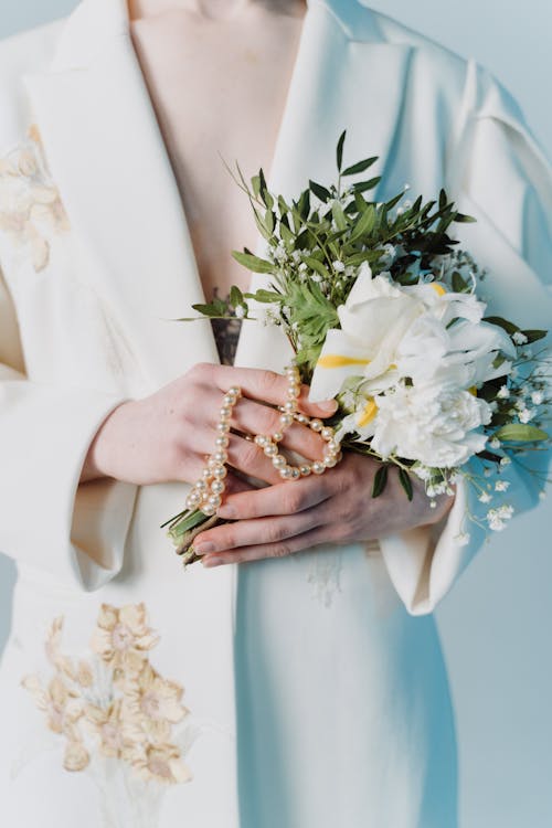 Free A Woman in White Blazer Holding White Flowers and Leaves Stock Photo