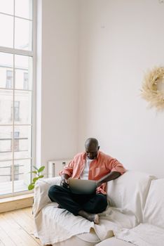 A person sitting comfortably with a laptop in a bright, minimalist living space, enjoying online activities.
