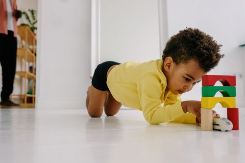 Free Young child engaged with toy blocks in a bright home setting, expressing creativity and fun. Stock Photo