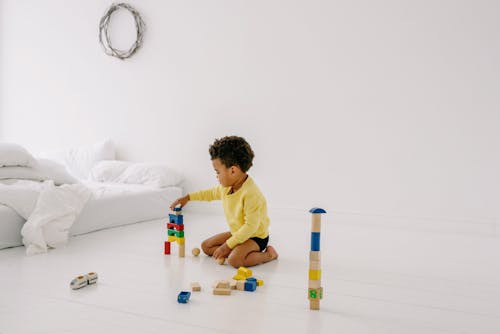 Free A Boy Playing with Wooden Toys on the White Floor Stock Photo