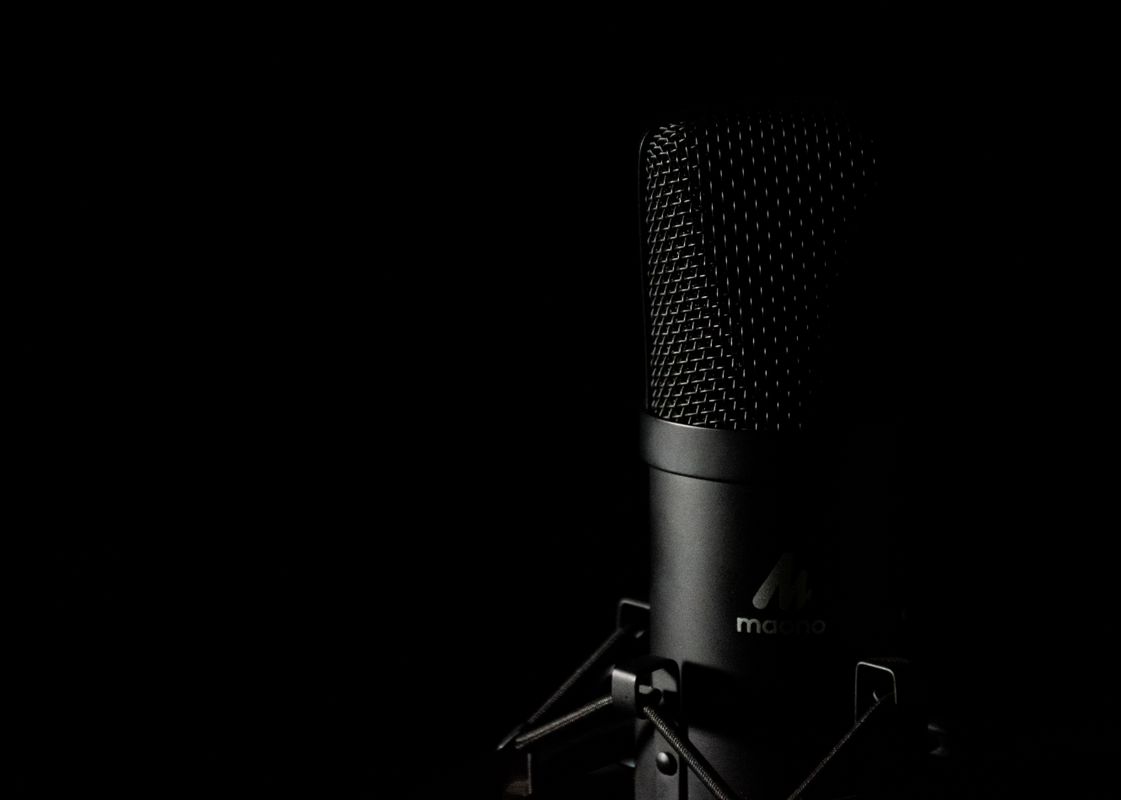 Detailed close-up of a studio microphone with a dark background, ideal for audio production themes.