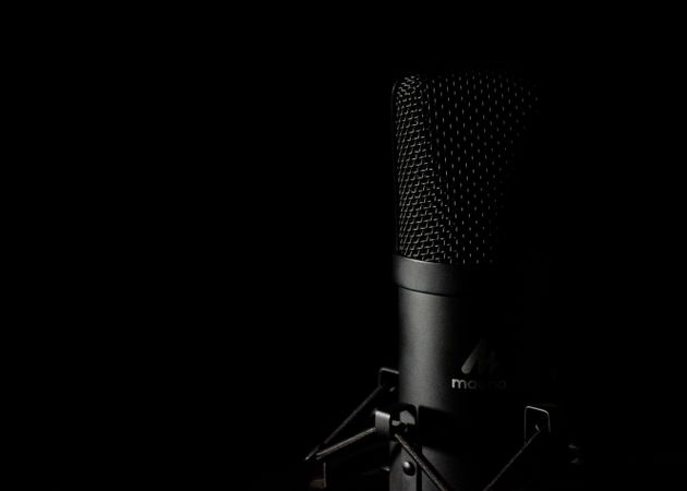 Detailed close-up of a studio microphone with a dark background, ideal for audio production themes.