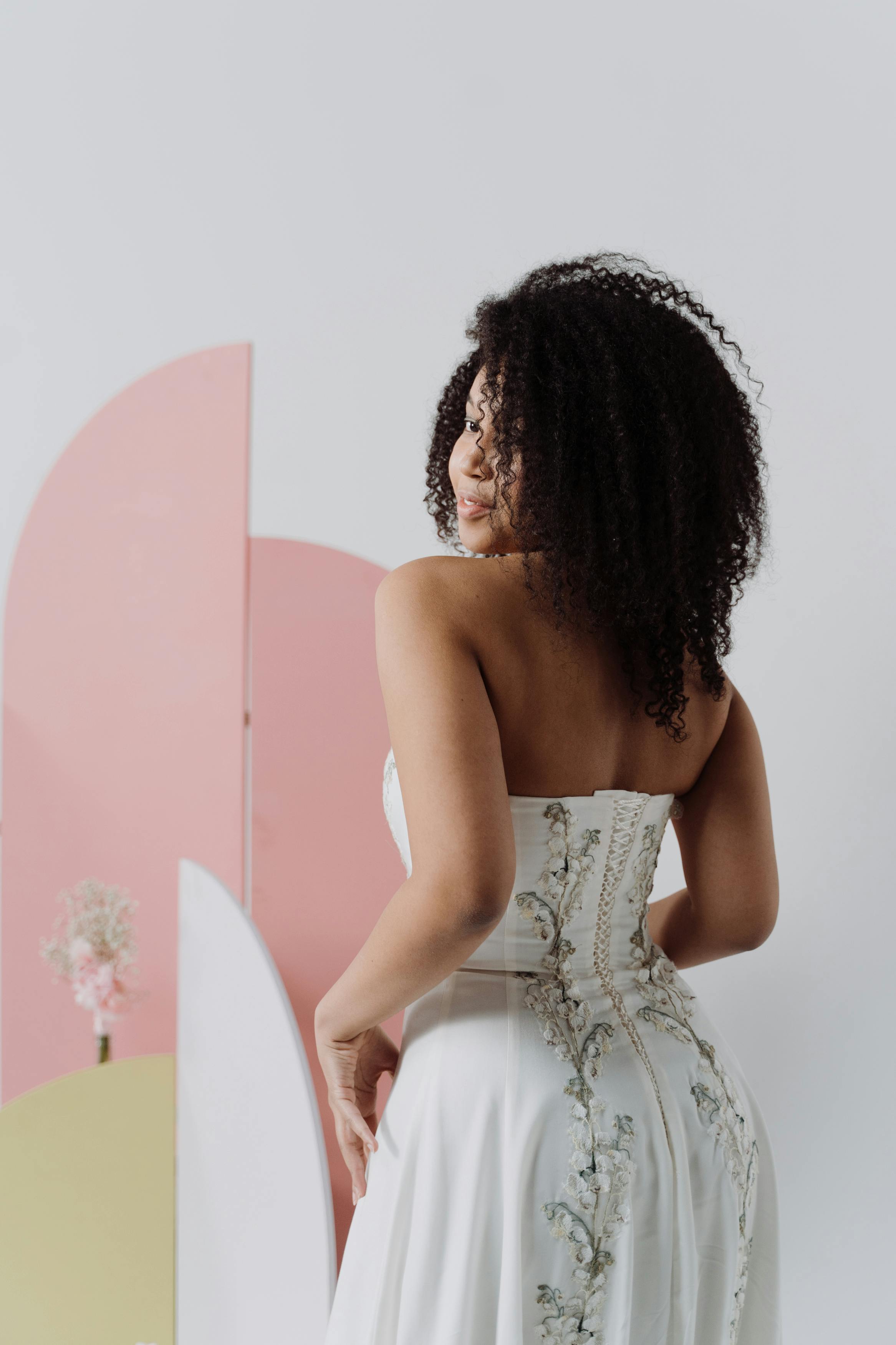 Stunning portrait of a bride in a wedding dress with curly hair, captured indoors.