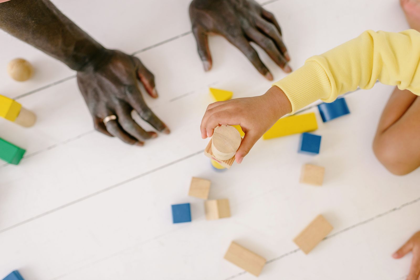 Parent and child creating a playful scene with wooden toys