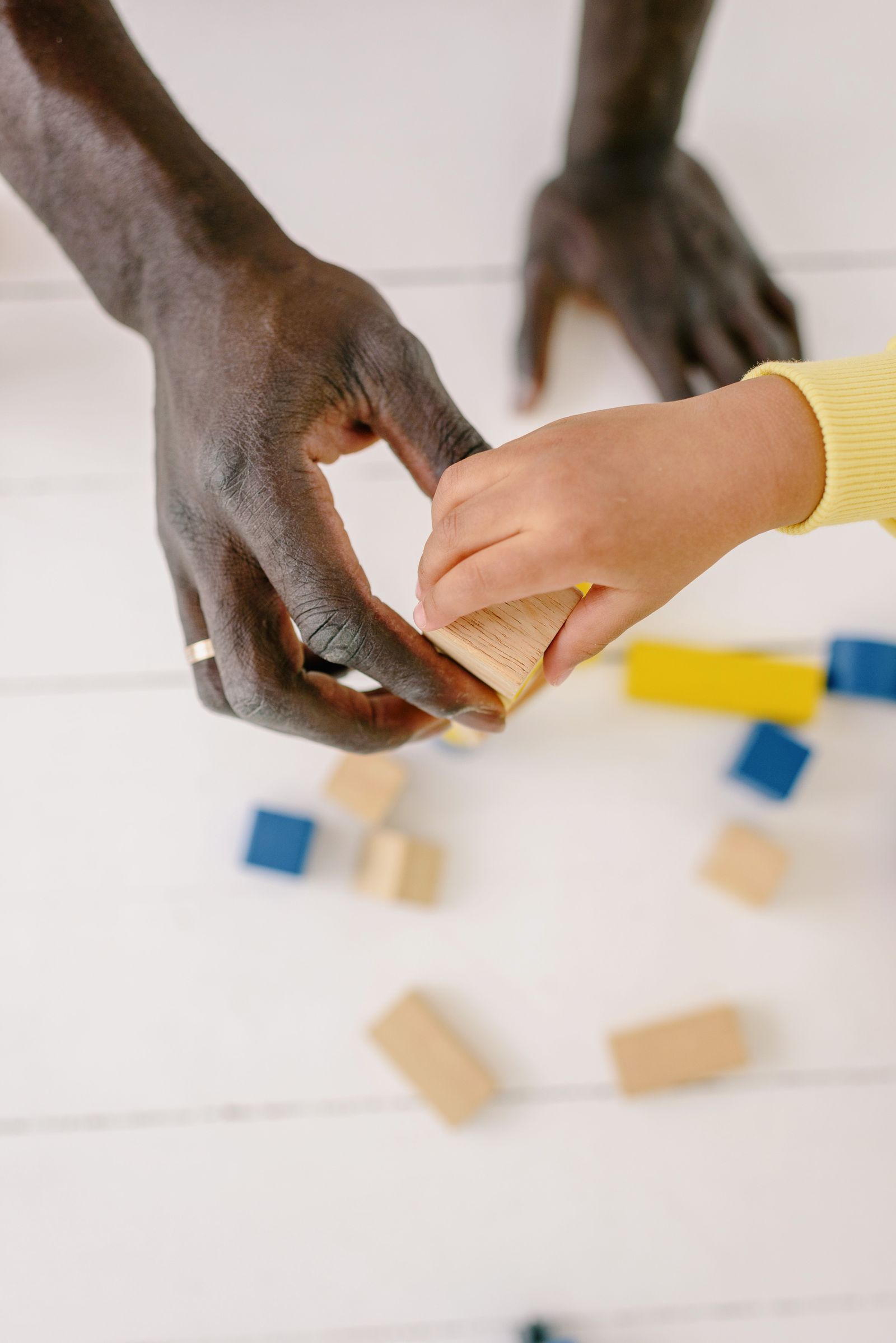 Adult and child carefully building with colorful wooden blocks