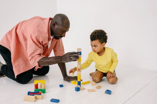 Free Father and son playing with wooden blocks indoors, enjoying quality family time together. Stock Photo