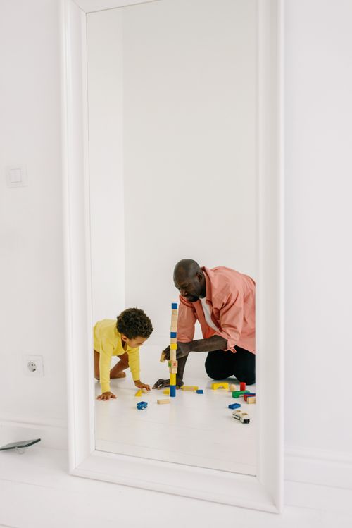 Free Father and son bonding while playing with colorful toy blocks in front of a mirror. Stock Photo