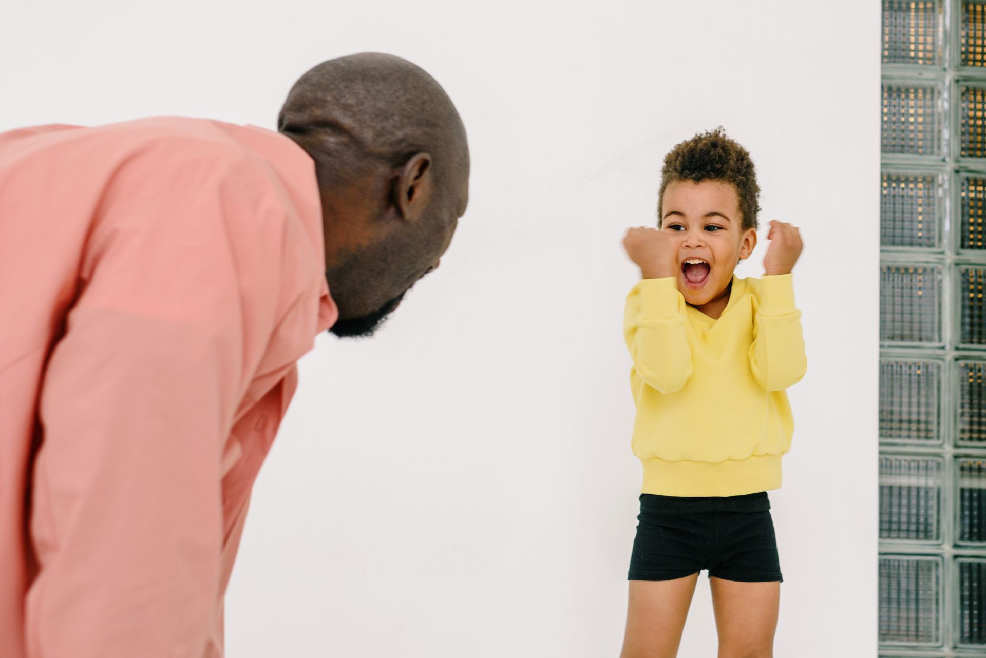 Happy African American father and son sharing a joyful moment indoors.