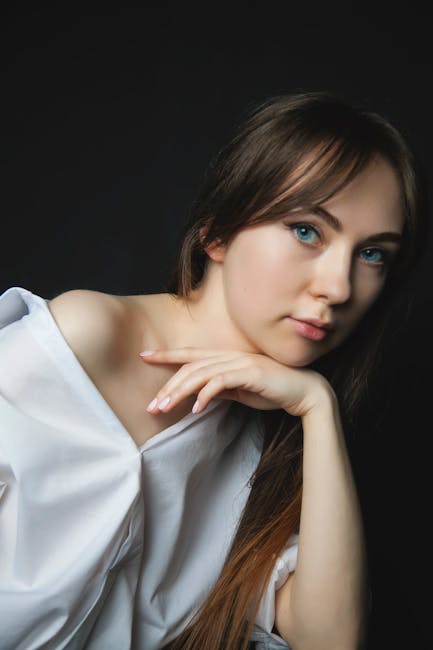 Captivating portrait of a young woman in a studio with a serene expression and stylish attire.