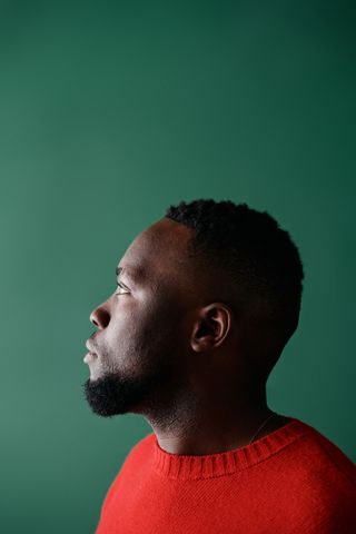 Profile portrait in a red knit against a green backdrop — photo by Norma Mortenson on Pexels