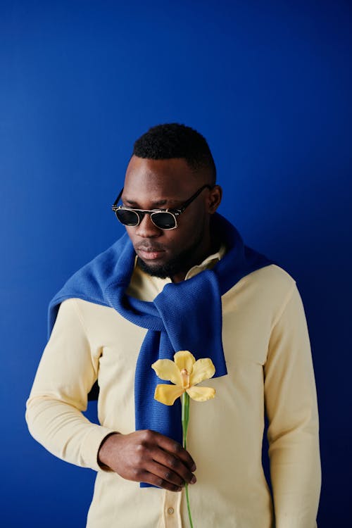 A Man with Yellow Flower Standing Beside the Blue Background