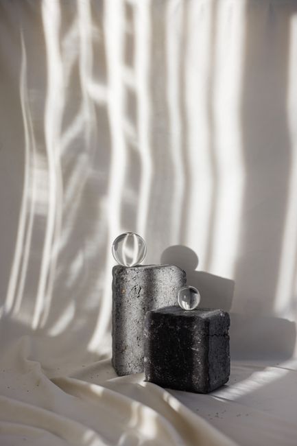 Artistic still life featuring glass spheres on concrete blocks with dramatic light play.