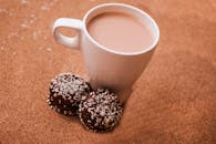 木桌上有一杯热可可，旁边放着巧克力和椰子饼干