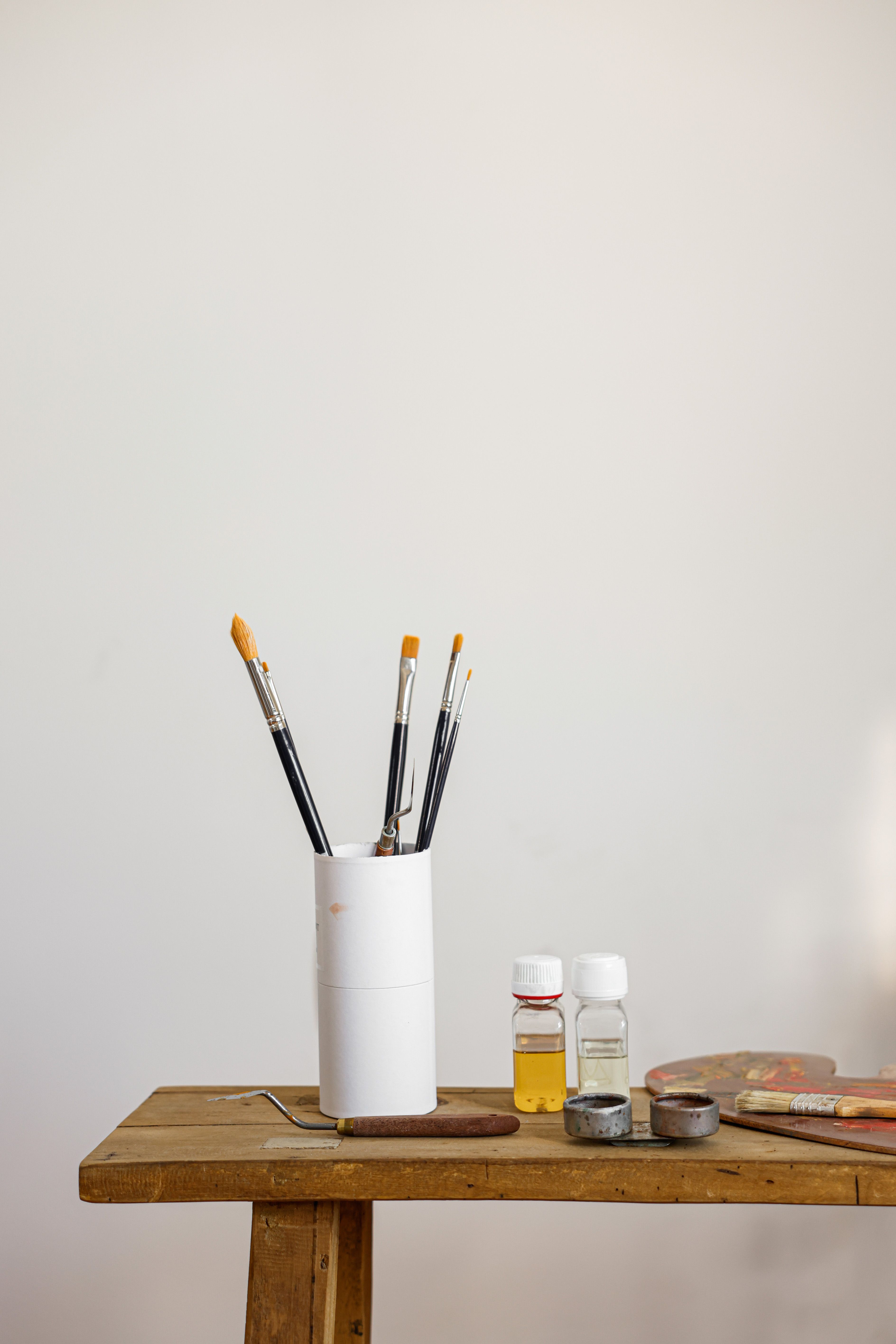 A minimalistic arrangement of paintbrushes and art supplies on a wooden table, ideal for creative projects.
