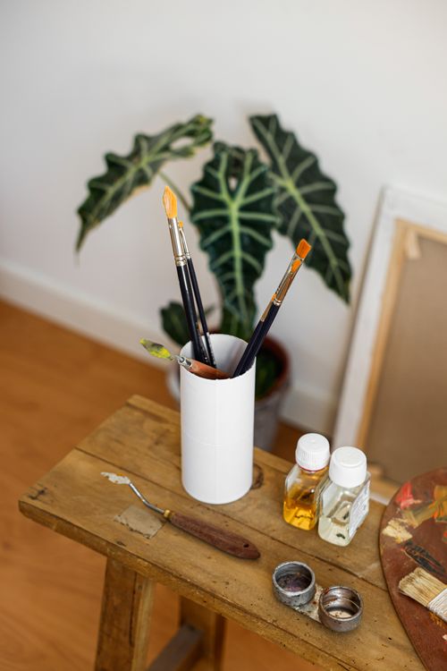 Free A cozy creative workspace with paintbrushes and art supplies on a wooden desk. Stock Photo