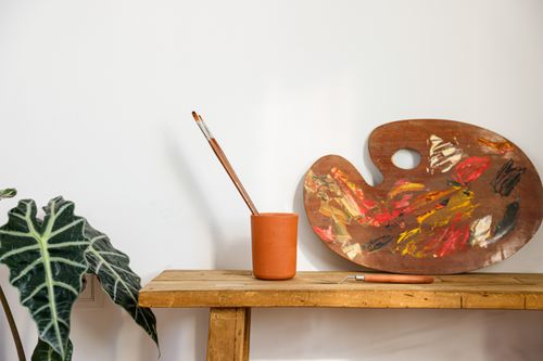 Free Artistic scene with a paint palette, brushes, and still life plant. Stock Photo