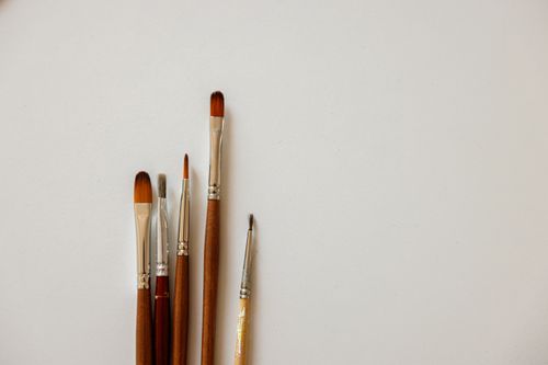 Free A collection of five paint brushes laid on a clean white surface, ideal for artistic purposes. Stock Photo