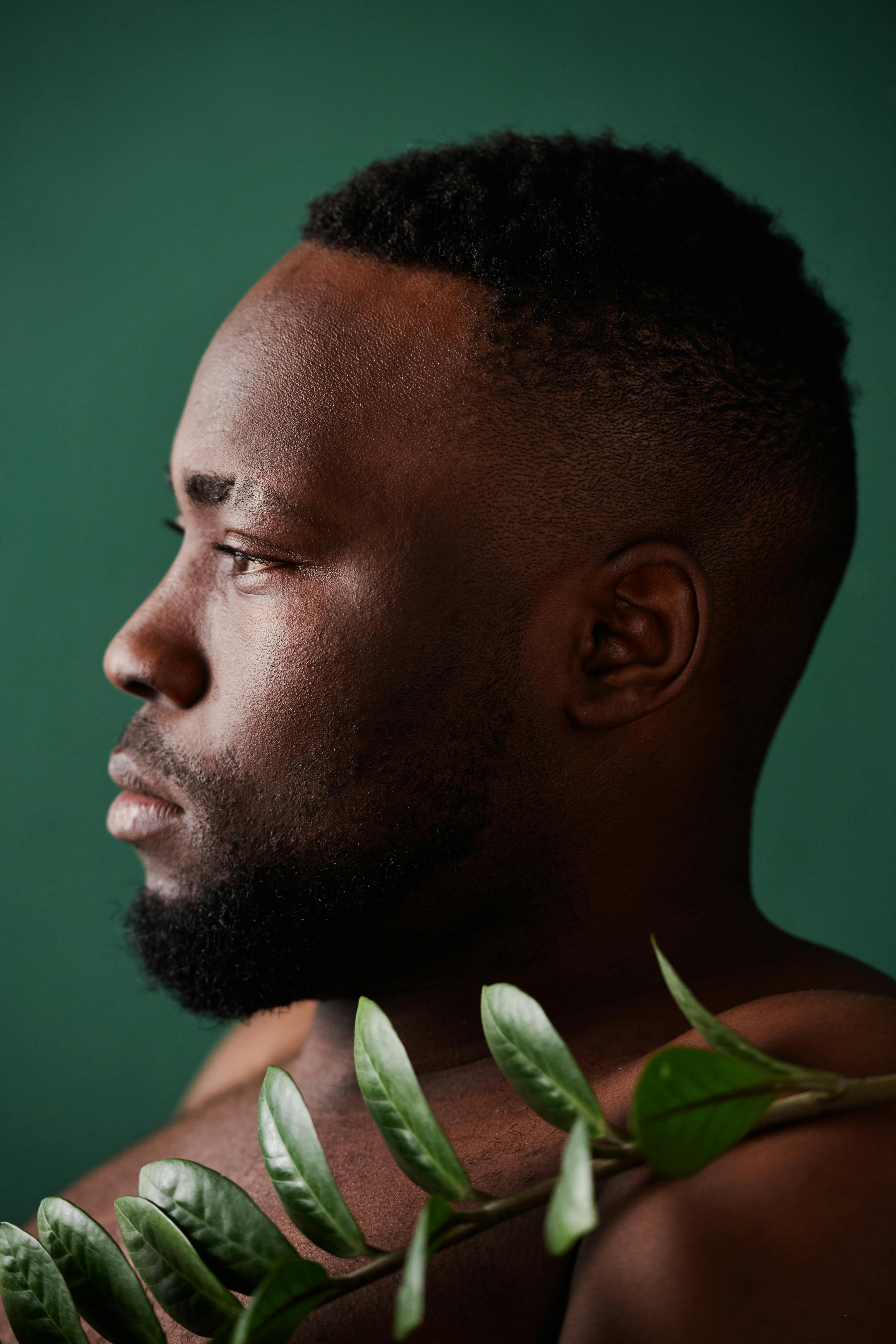 Side profile of a bearded man against a green background, embracing nature.