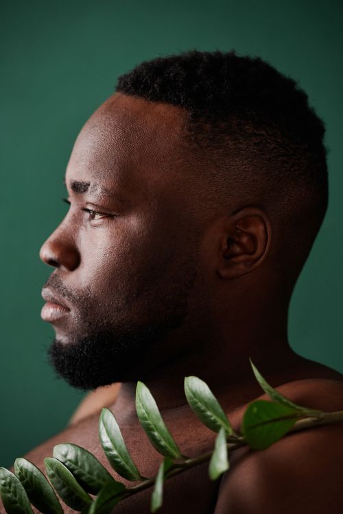 Free Side profile of a bearded man against a green background, embracing nature. Stock Photo