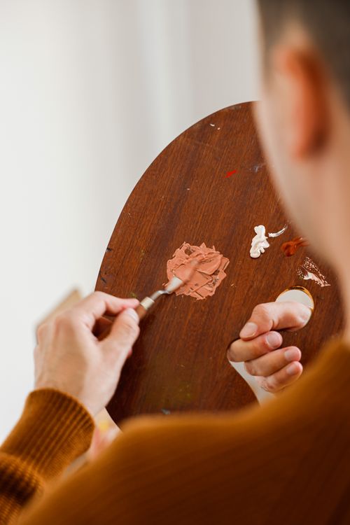 Free Close-up of an artist mixing colors on a wooden palette using a palette knife. Stock Photo