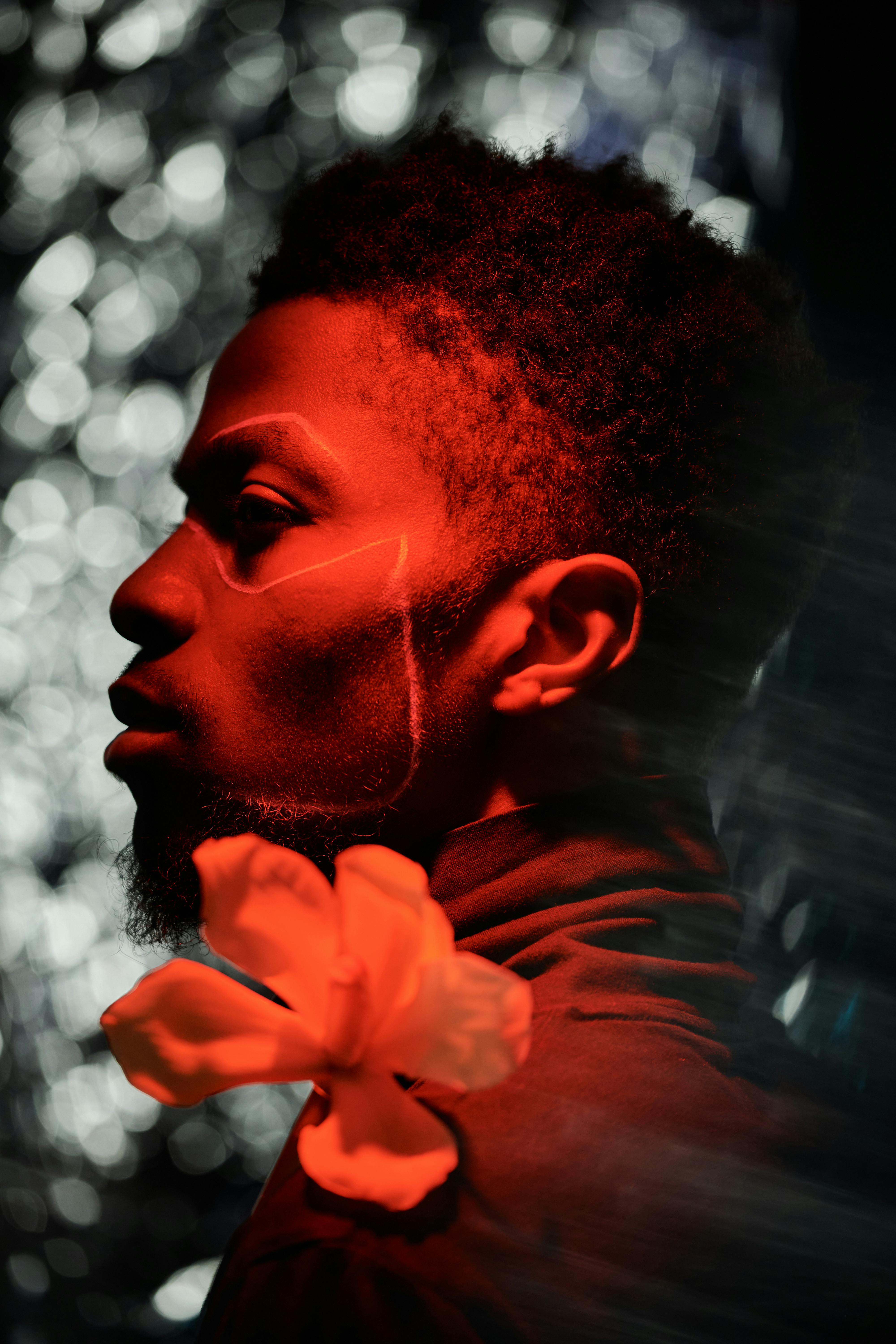 Dramatic side view portrait of a man with red lighting and bokeh background.