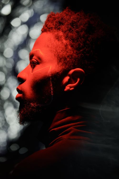 Free Artistic side portrait of a man illuminated by red light, creating a dramatic and mysterious mood. Stock Photo