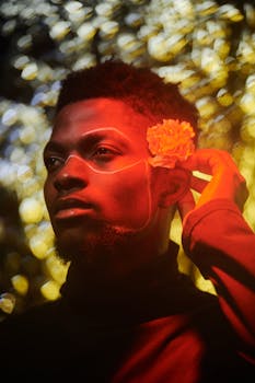 Expressive portrait of a man with art makeup and a flower in dramatic light.