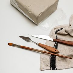 A block of pale clay with palette knives on a linen cloth