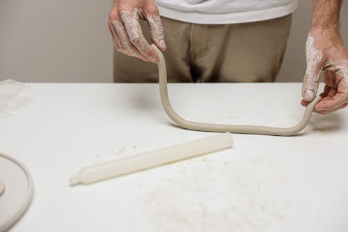 A Person Molding Clay on White Surface