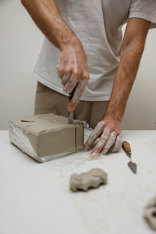 Free A craftsperson skillfully slices clay, showing expertise in ceramic creation. Stock Photo