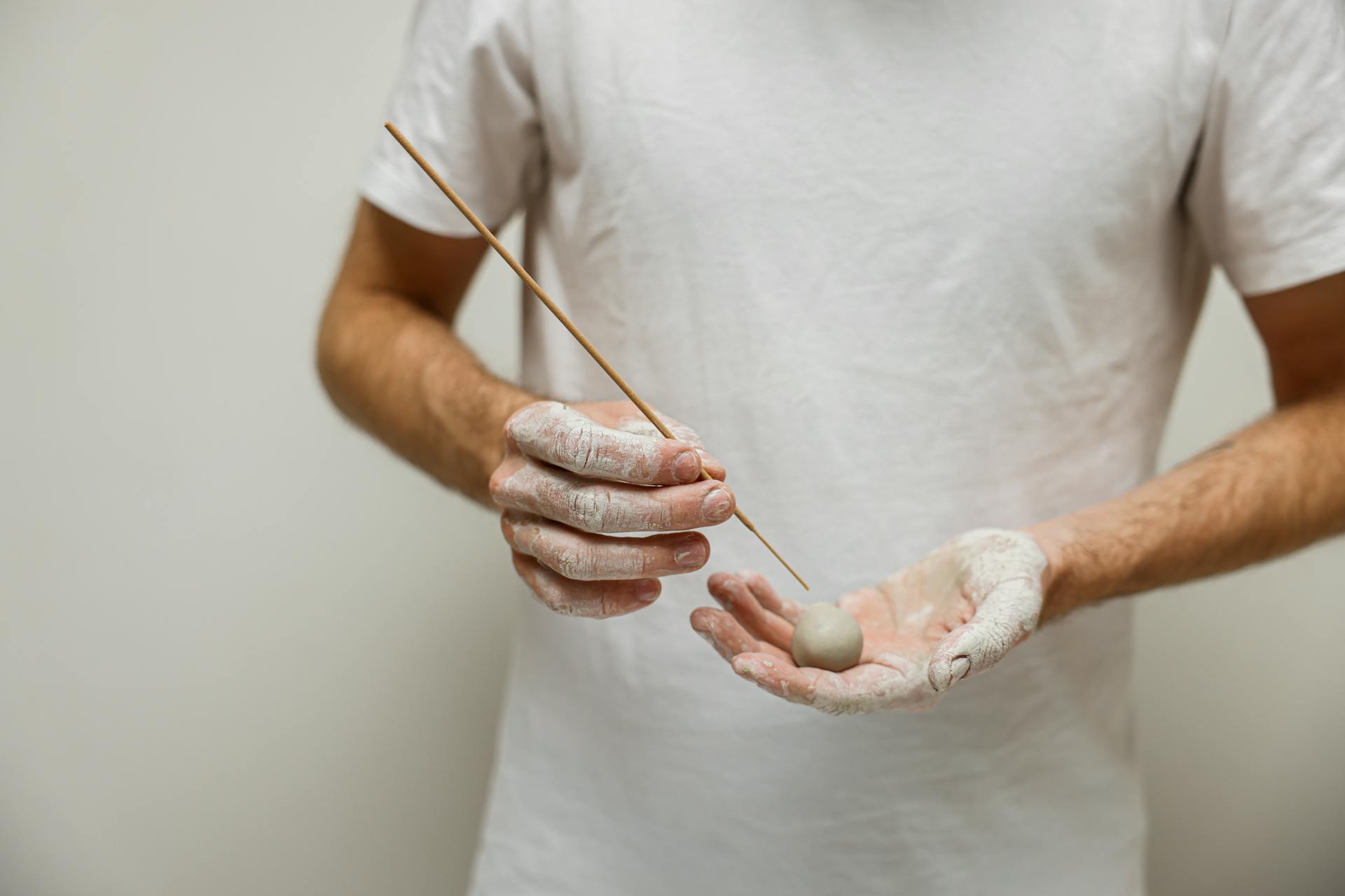 A Man Holding a Clay Ball and a Stick