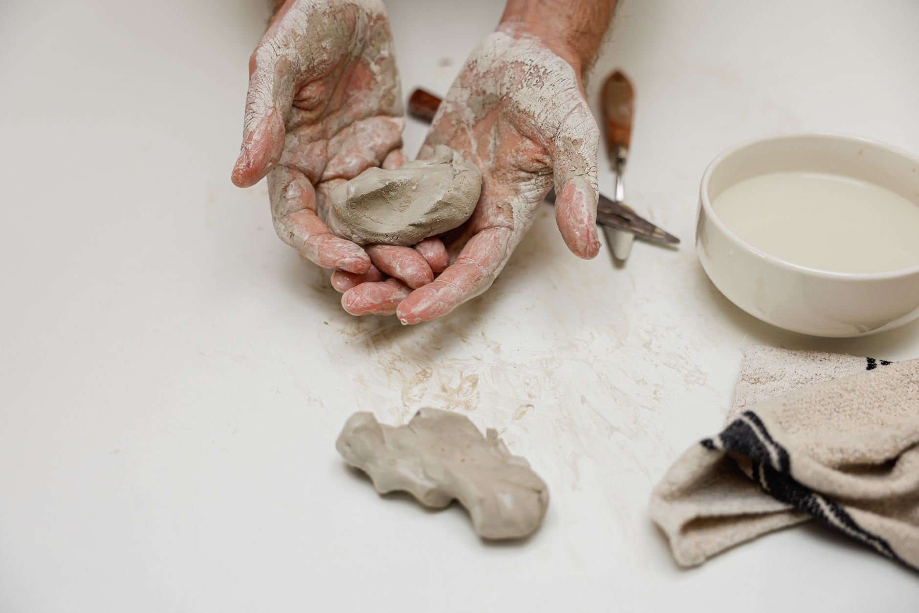 Close-up of a potter's hands shaping clay, showcasing the creative process in a ceramics studio.