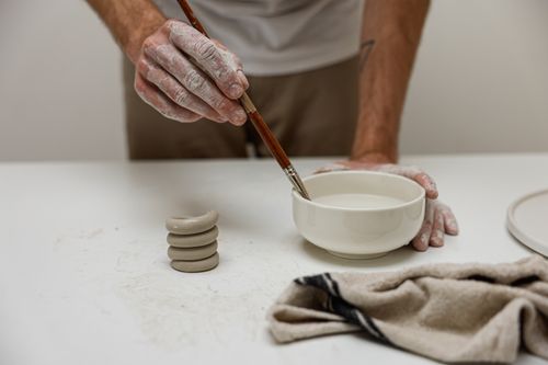 Free Close-up of an artist painting a ceramic bowl with precise handwork and craftsmanship. Stock Photo
