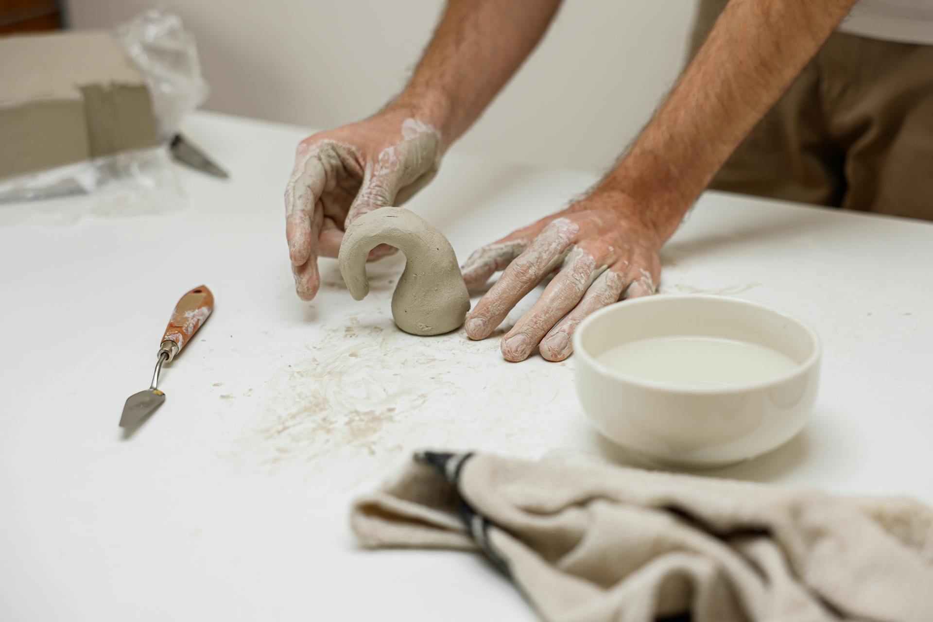 Close-up of hands crafting clay pottery in a creative workspace. Artistic handmade process captured in detail.