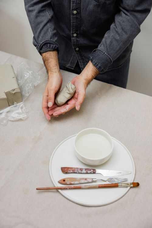 Free Close-up of a ceramist molding clay with pottery tools on a table. Stock Photo