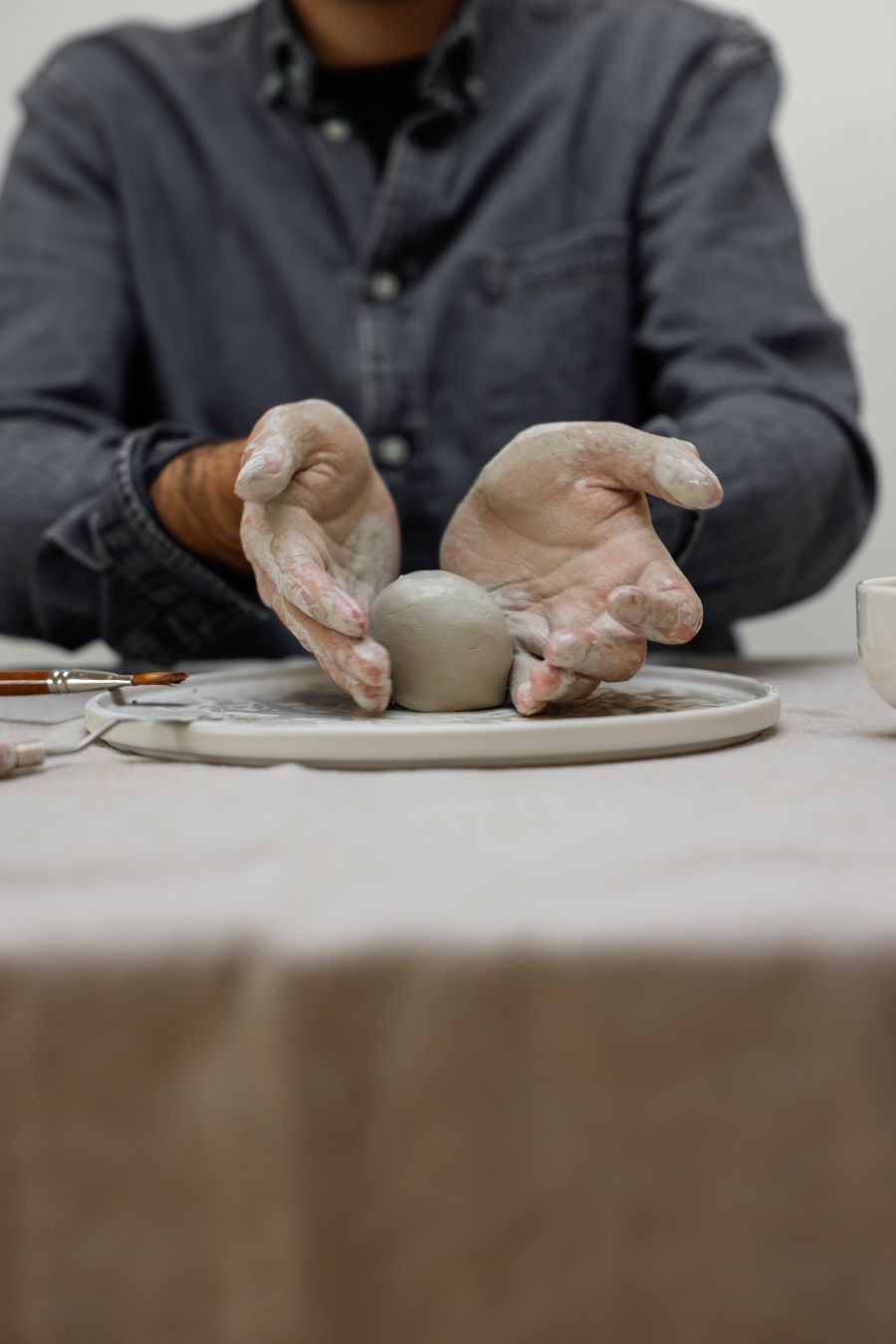 Artist's hands cradling a ball of fresh clay above a pottery wheel