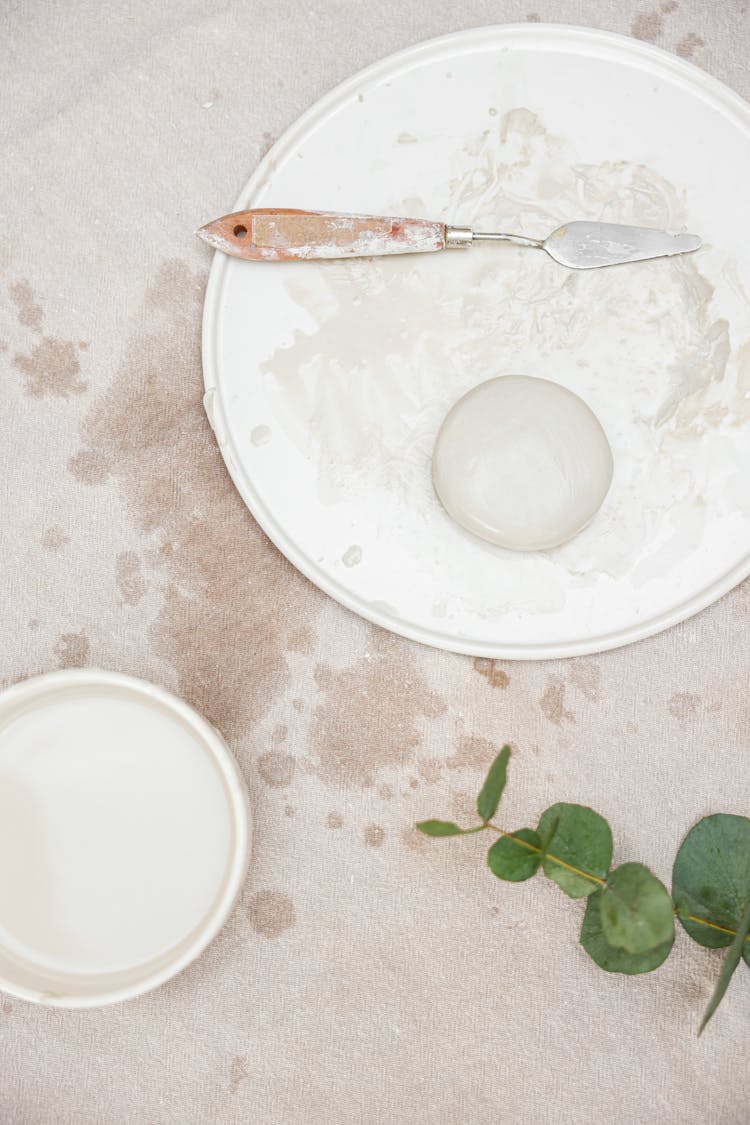 A Ball Of Clay Lying On A Tray Next To A Spatula 