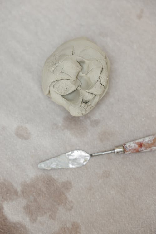 Close-up Photo of Palette Knife beside a Clay 