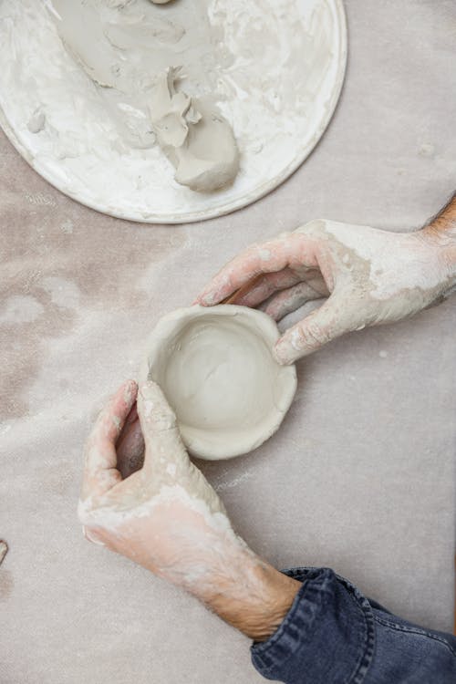 Hands Crafting a Clay Bowl on Table