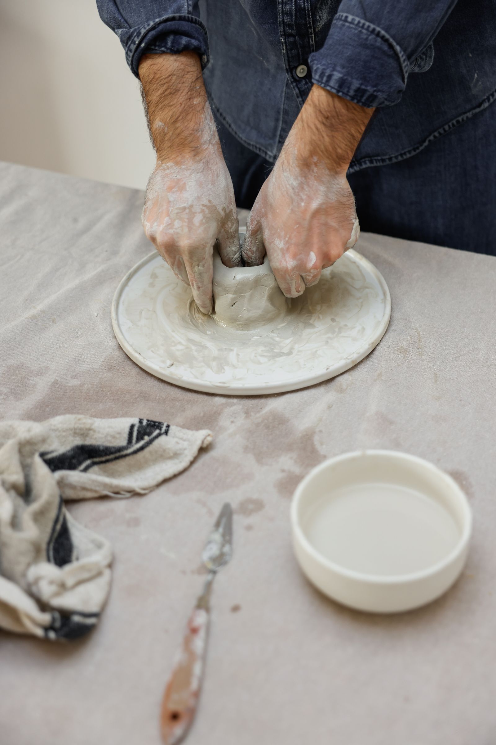 Hands shaping a small clay bowl
