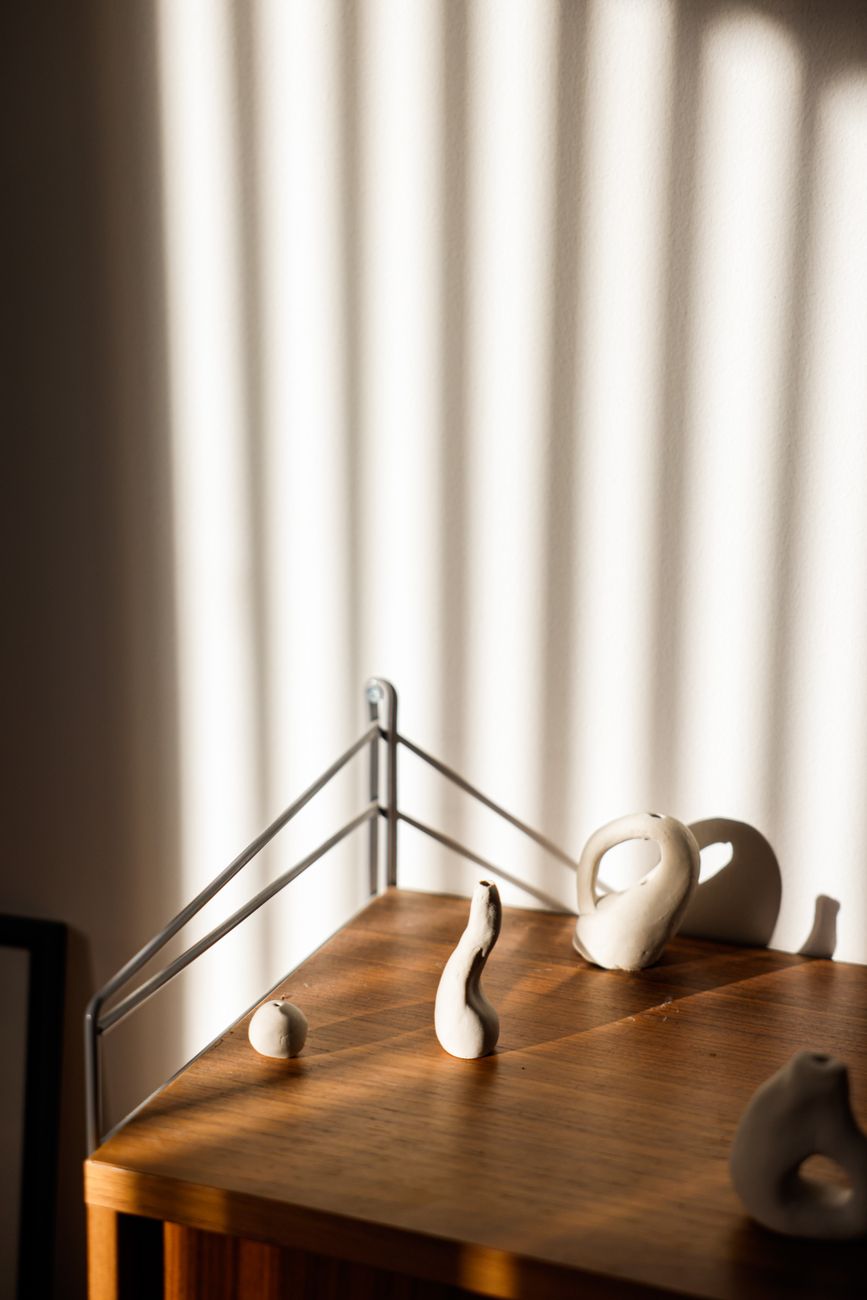 Minimalist ceramic sculptures with dramatic shadows on a wooden table.