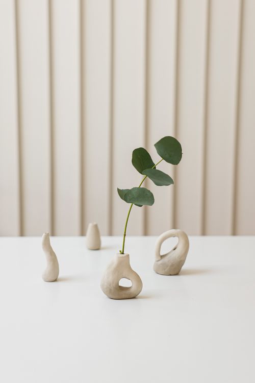 Free Elegant minimalist arrangement of ceramic vases with a single leaf against a neutral background. Stock Photo